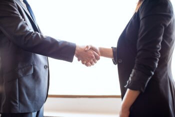 FAQ: Wie bewerbe ich mich für einen Studienplatz? Studentin und Arbeitgeber schütteln sich die Hand