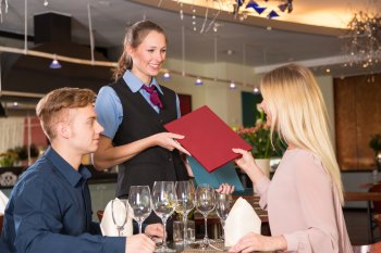Restaurantfachfrau bringt Gästen die Speisekarte