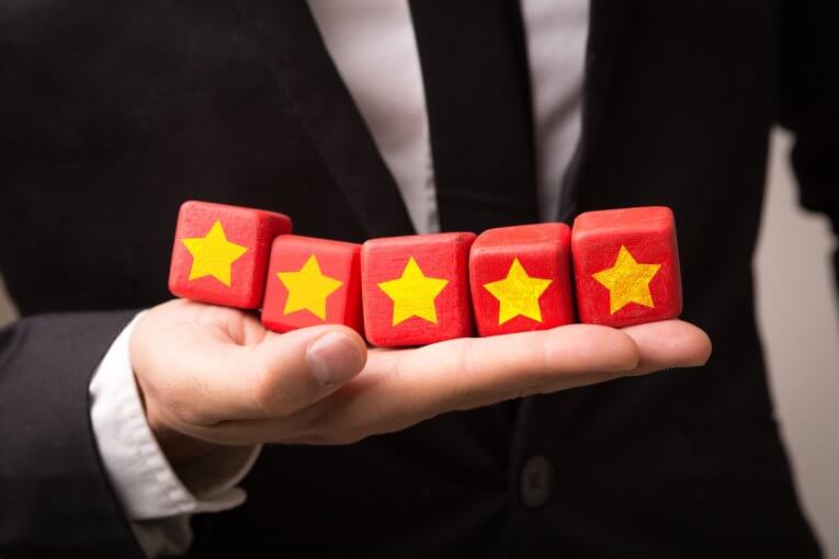 Mann im Anzug hält fünf Würfel mit Sternmotiv in der Hand